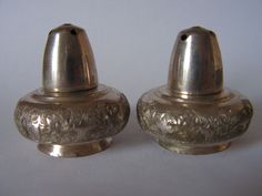 two silver salt and pepper shakers sitting side by side