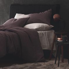 a bed with brown sheets and pillows on top of it next to a night stand