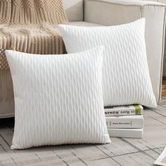 two white pillows sitting next to each other on a couch