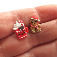 two miniature gingerbreads in the palm of someone's hand, one wearing a santa hat