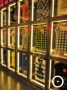 there are many shirts on display in the store window, all different colors and sizes