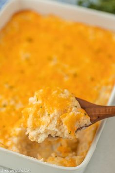 a spoon full of mashed potatoes in a casserole dish