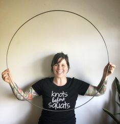 a woman holding a hoop with tattoos on her arms