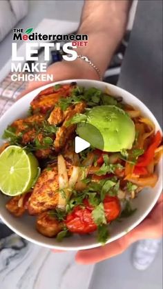 a person holding a white bowl filled with chicken and veggies next to a lime wedge