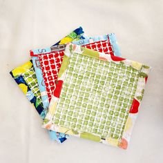 three pieces of fabric are sitting on top of each other, one is green and the other is red