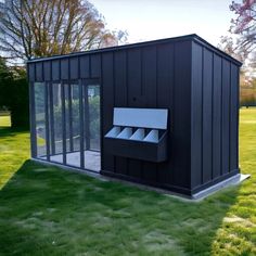 a black outhouse sitting on top of a lush green field