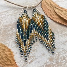 a pair of beaded earrings hanging from a string on top of a wooden table