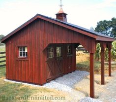 a small red barn with a steeple on the top and an open front door