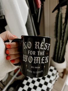 a woman holding a black coffee mug with the words no rest for the women on it