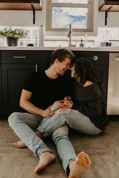 a man and woman sitting on the floor in a kitchen with their feet up to each other