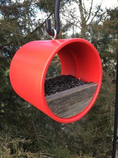 a red bird feeder hanging from a tree