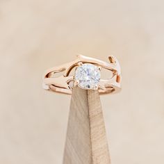 a close up of a ring on top of a piece of wood with a diamond in the center