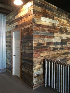 an empty room with a radiator and wooden wall in the corner, next to a door