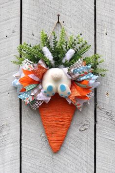 a carrot shaped decoration hanging on the side of a wooden fence