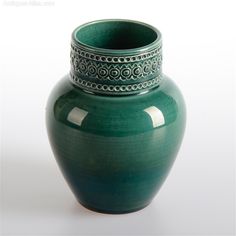 a green vase sitting on top of a white table