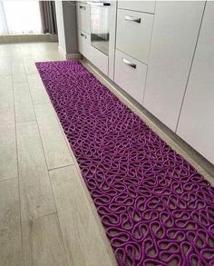 a purple rug in the middle of a kitchen floor next to white cabinets and drawers