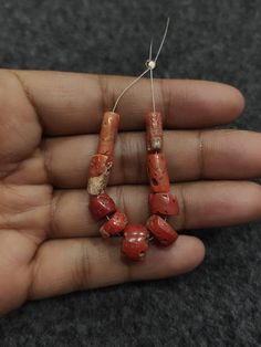 a person is holding some red beads in their hand and it looks like they have been made out of clay