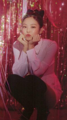 a woman sitting in front of balloons with her chin resting on her hand while looking at the camera