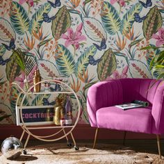 a pink chair sitting in front of a wallpaper