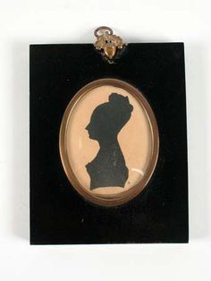 the silhouette of a woman in a black and gold frame is mounted on a white wall