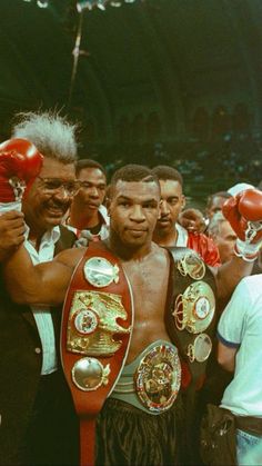 two men standing next to each other with boxing gloves on their shoulders and one holding a red glove