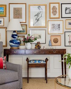 a living room filled with furniture and framed pictures on the wall behind a table covered in vases