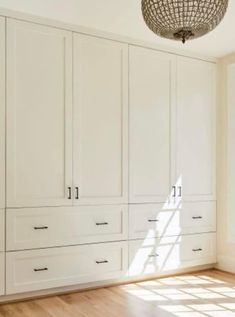 an empty room with white cabinets and wood floors