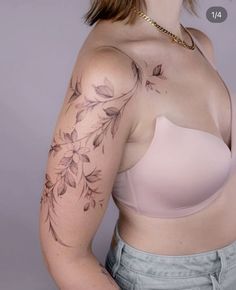 a woman with a tattoo on her arm and breast is standing in front of a gray background