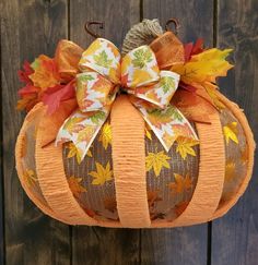 an orange pumpkin decorated with fall leaves and a bow