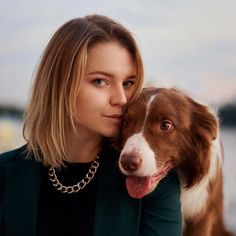 a woman and her dog are posing for a photo in front of the water with their heads close to each other