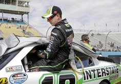 a man sitting in the driver's seat of a race car at a track