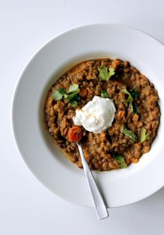 a white bowl filled with food on top of a table next to a fork and knife