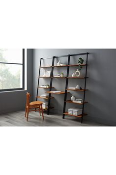 an empty room with a ladder shelf and chair next to the window in front of it