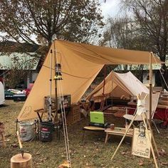 a tent set up in the middle of a field with other tents and tables around it