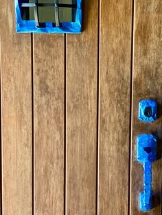 the door is made out of wood and has two blue blocks on it, one with a letter