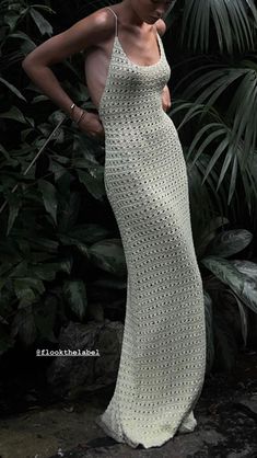 a woman standing in front of some plants wearing a white crocheted dress and holding her hand on her hip