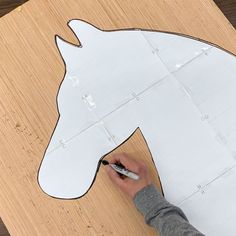 someone is cutting out a paper horse head on the floor with a pen and scissors