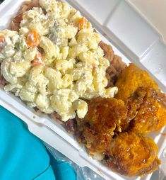 a plastic container filled with chicken wings, macaroni and cheese salad and carrots