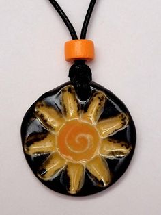 an orange and black necklace with a sun design