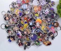 a bunch of anime key chains sitting on top of a white table next to a plant