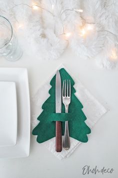 a place setting with christmas tree napkins and silverware