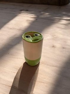 a green and white cup sitting on top of a wooden table