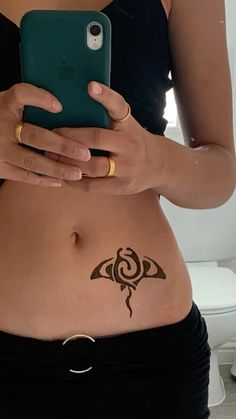 a woman with a tattoo on her stomach holding a cell phone