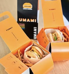 three orange boxes with hamburgers and french fries in them