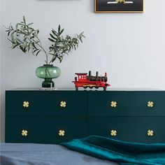 a green dresser with a red toy train on it and two pictures above the drawers