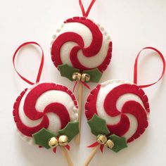 three red and white ornaments on sticks with bells attached to them, sitting next to each other