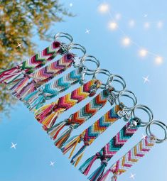 a bunch of key chains that are hanging from a tree with lights in the background