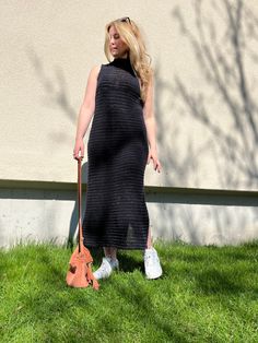 a woman in a black dress holding an umbrella and walking her dog on the grass