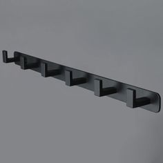 a black metal shelf with five hooks on it