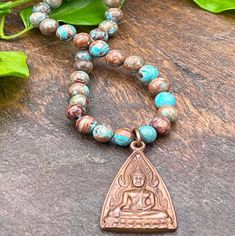 Wear this gorgeous handmade necklace to your next beach party or BBQ, and your friends will think you just returned from Thailand.  Indeed, the copper Buddha amulet was made by hand by Thai artisans, and adorns our Crazy Lace Agate 108 bead gemstone mala necklace.  Crazy Lace Agate gemstones have gorgeous sky and ocean blue turquoise colors, mixed with tans and browns. A perfect addition or souvenir, you choose, to your boho or spiritual jewelry collection. -Gemstone mala necklace composed of 108 6mm round Crazy Lace Agate gemstone beads with 1 handcrafted Ethiopian brass metal counter bead, and 2 copper beads up-cycled from an antique Thai prayer necklace. -Approximately 25 inches in length. -Pendant 1 inch long including ring. -Clasp-less, slips overhead, hand strung with silk or nylon t Sky And Ocean, Buddha Pendant Necklace, 108 Mala Beads, Buddha Pendant, Tibetan Buddhist, 108 Bead, Mala Necklace, Agate Necklace, Crazy Lace Agate